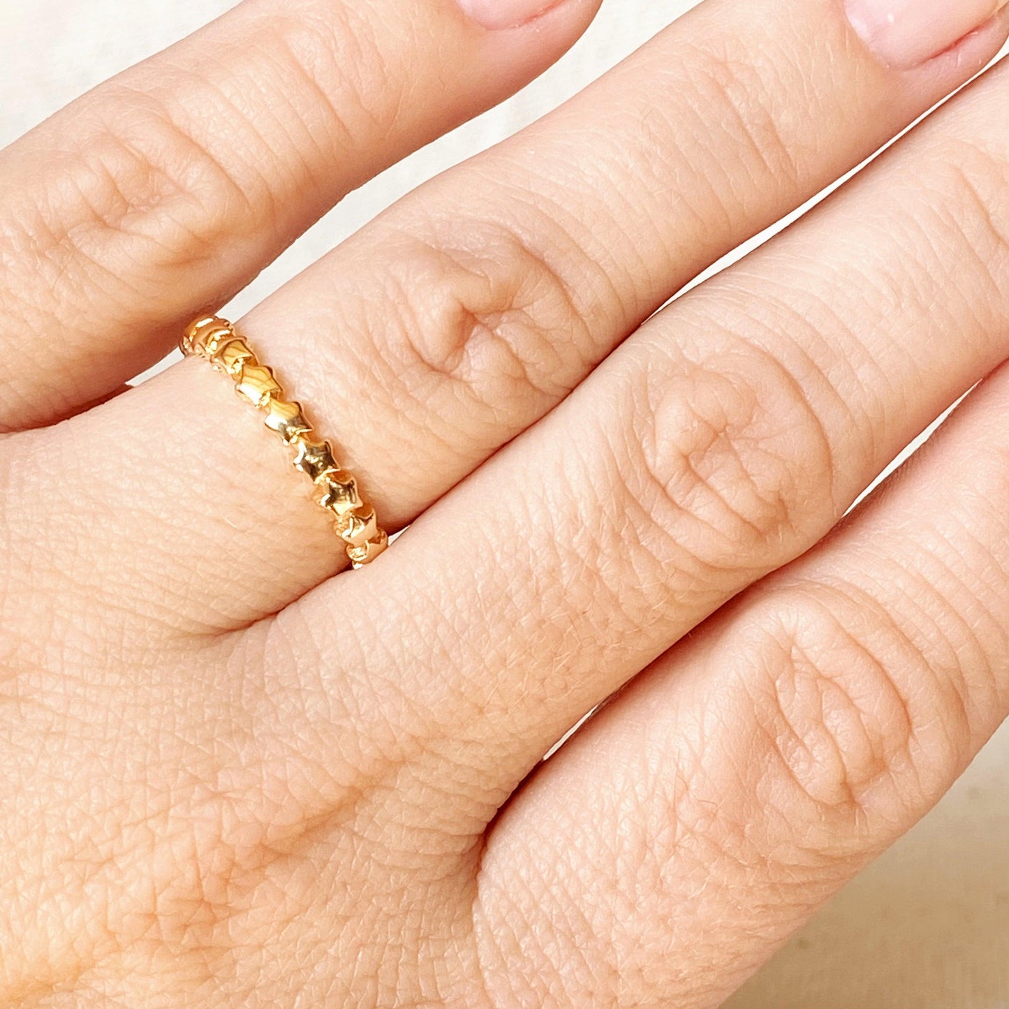 Gold ring on a person's finger with a white background