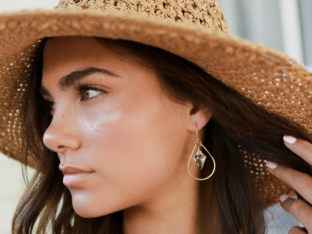 Woman wearing a straw hat and gold earring with a blurred background