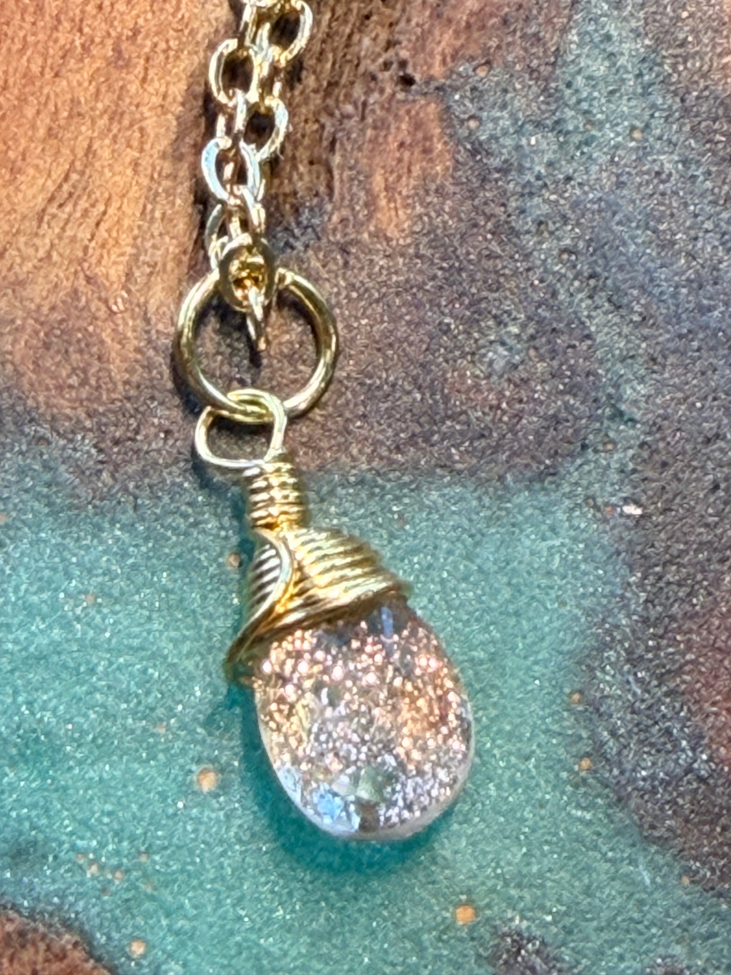 Gold Necklace with a glittery copper-infused quartz pendant on a textured surface