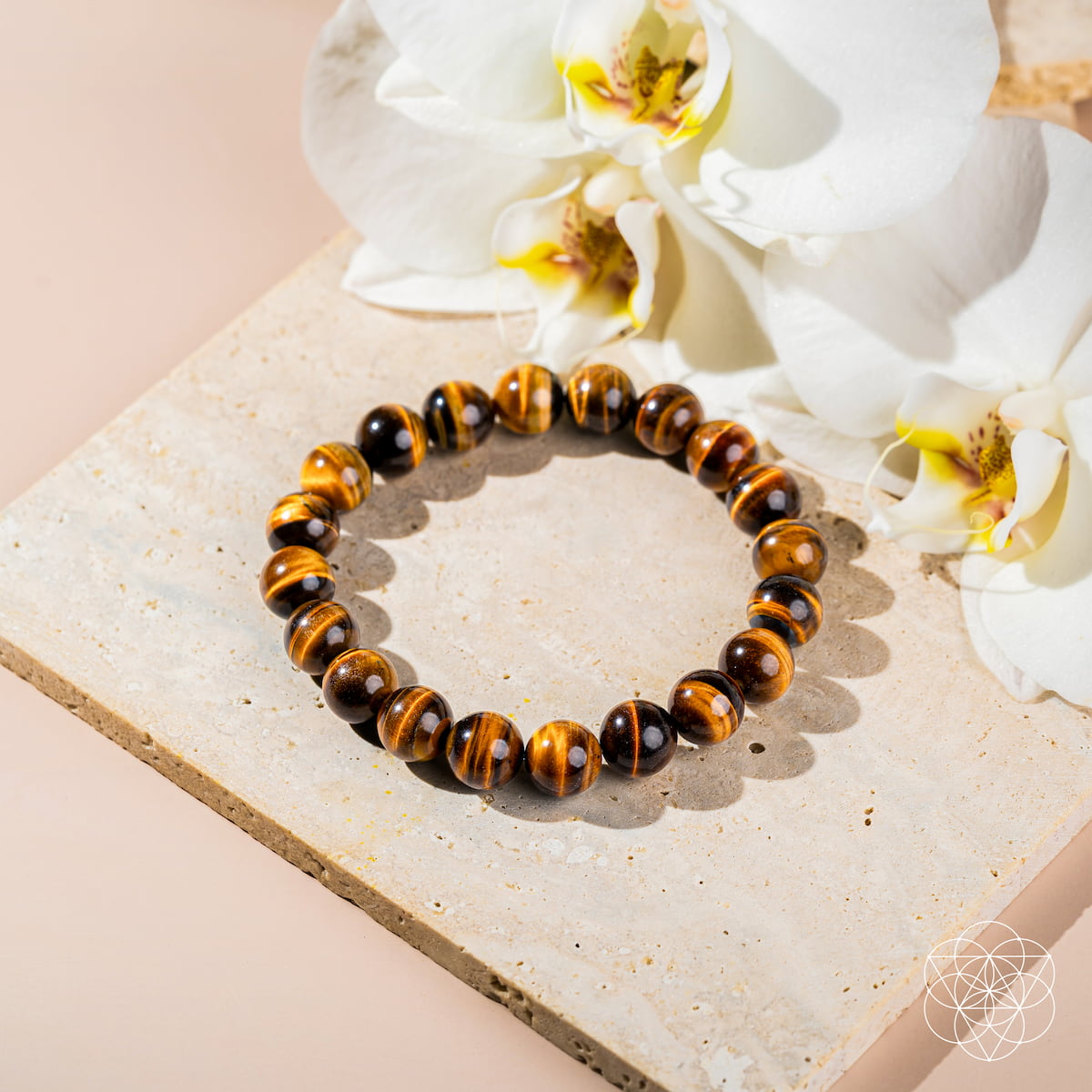 Tiger eye bracelet on a stone surface with white flowers