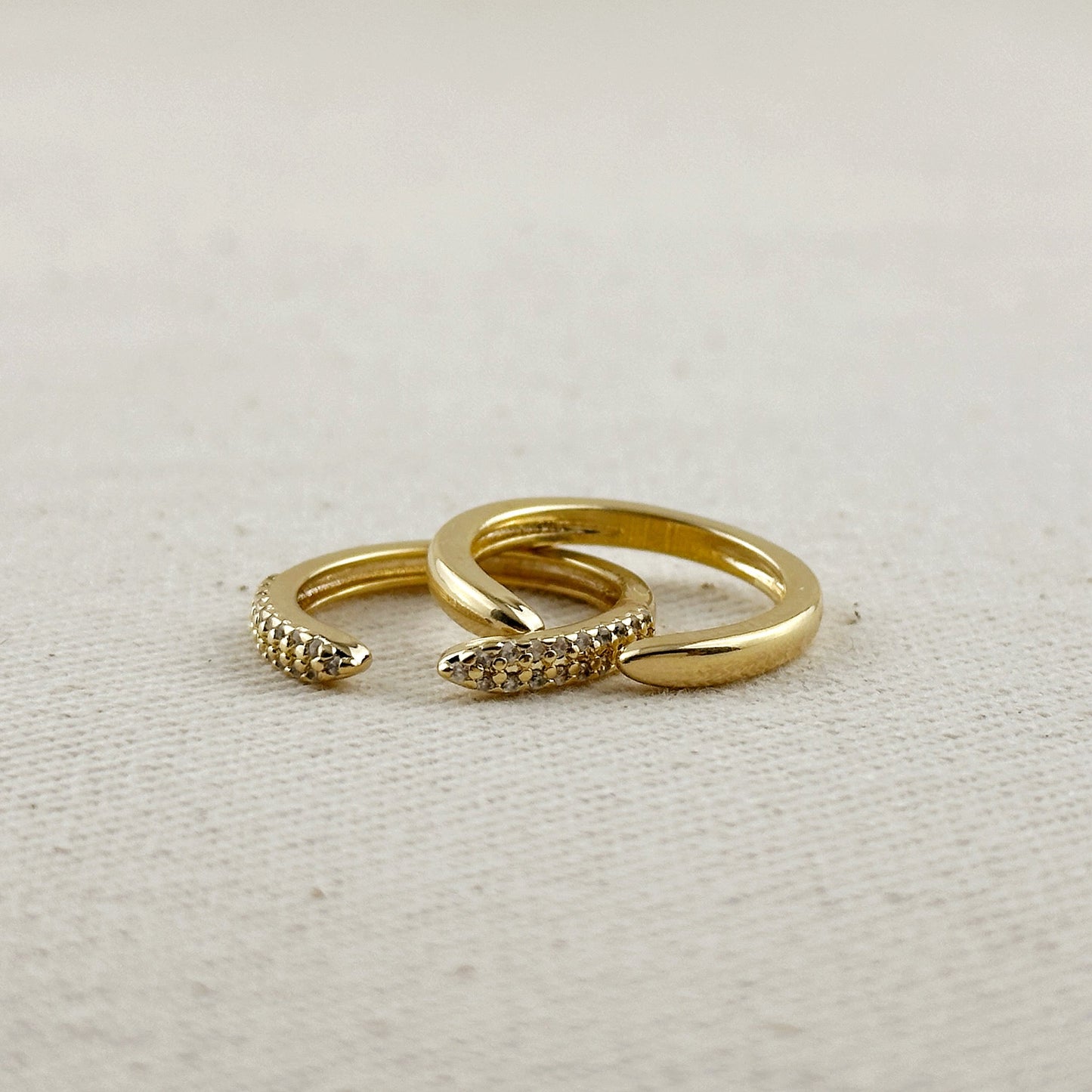 Gold snake-shaped ring on a textured beige surface