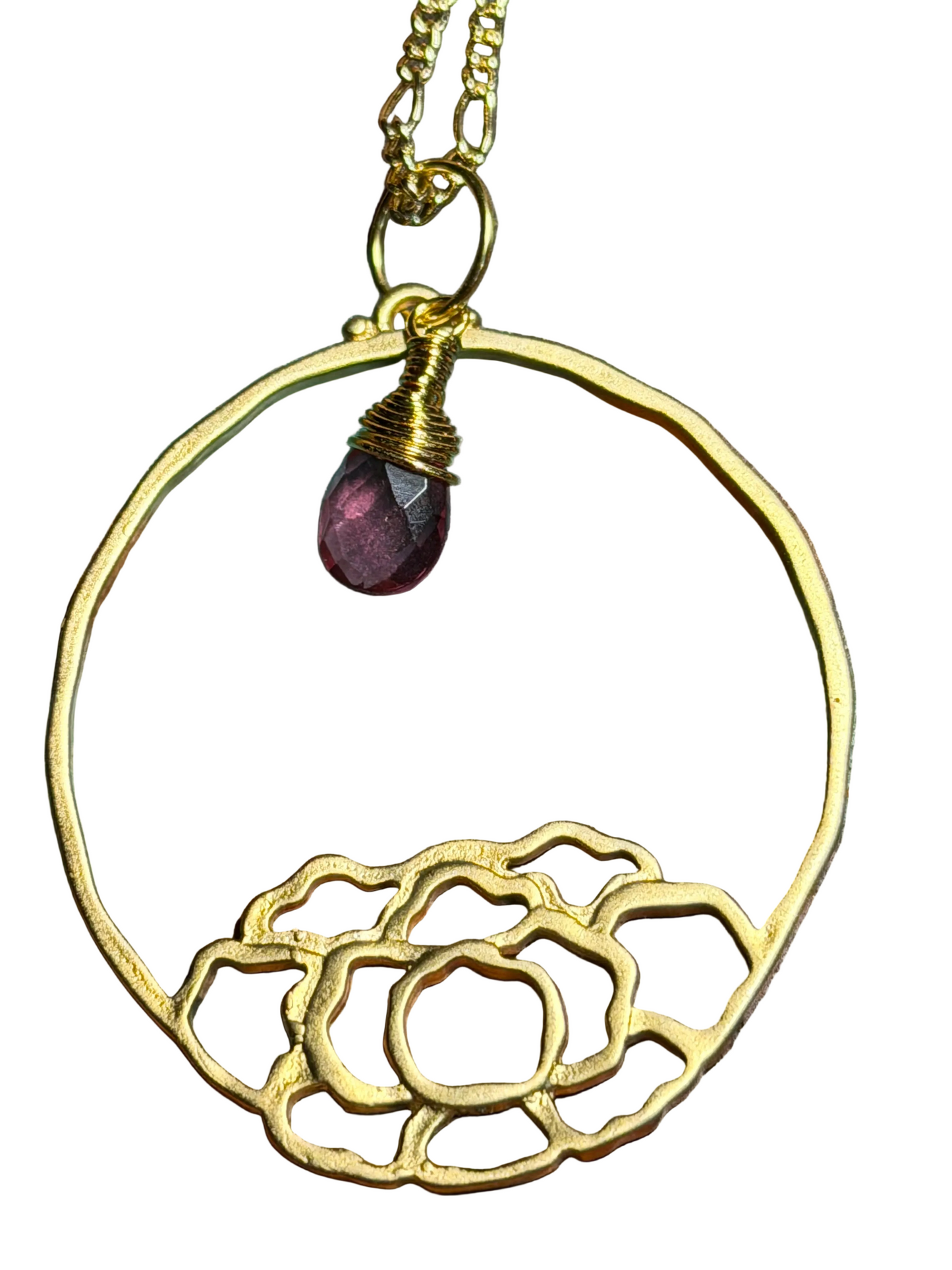 Gold necklace with a floral design and purple gemstone on a wooden surface