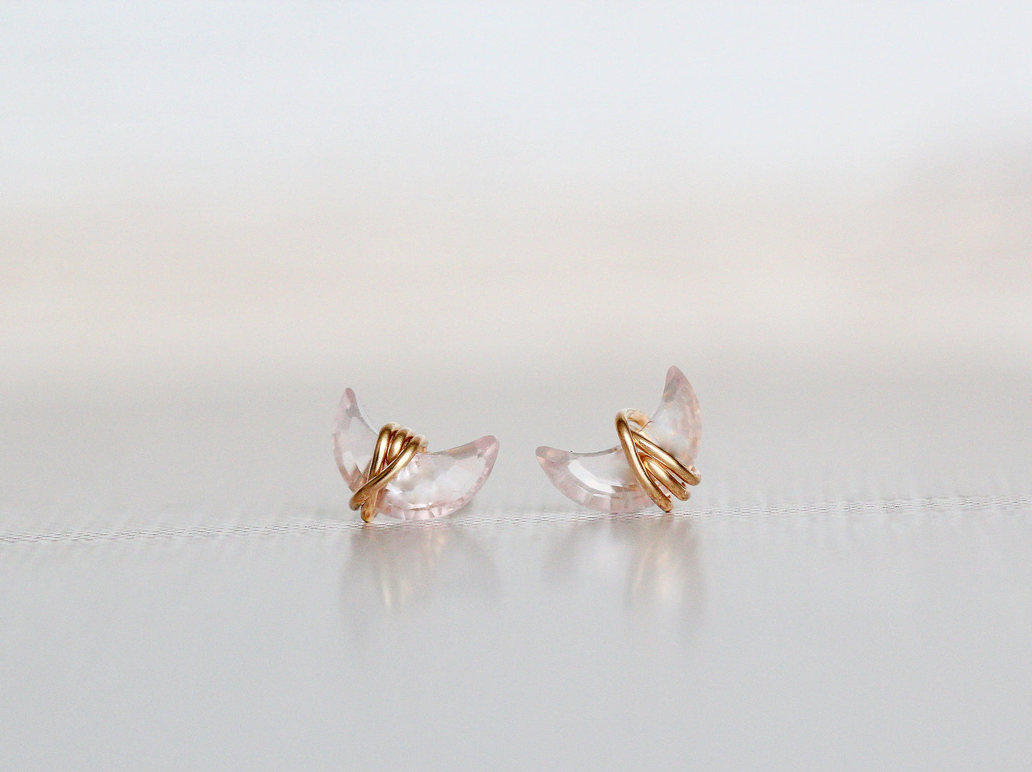 Pair of gold and clear crystal earrings on a light gray background