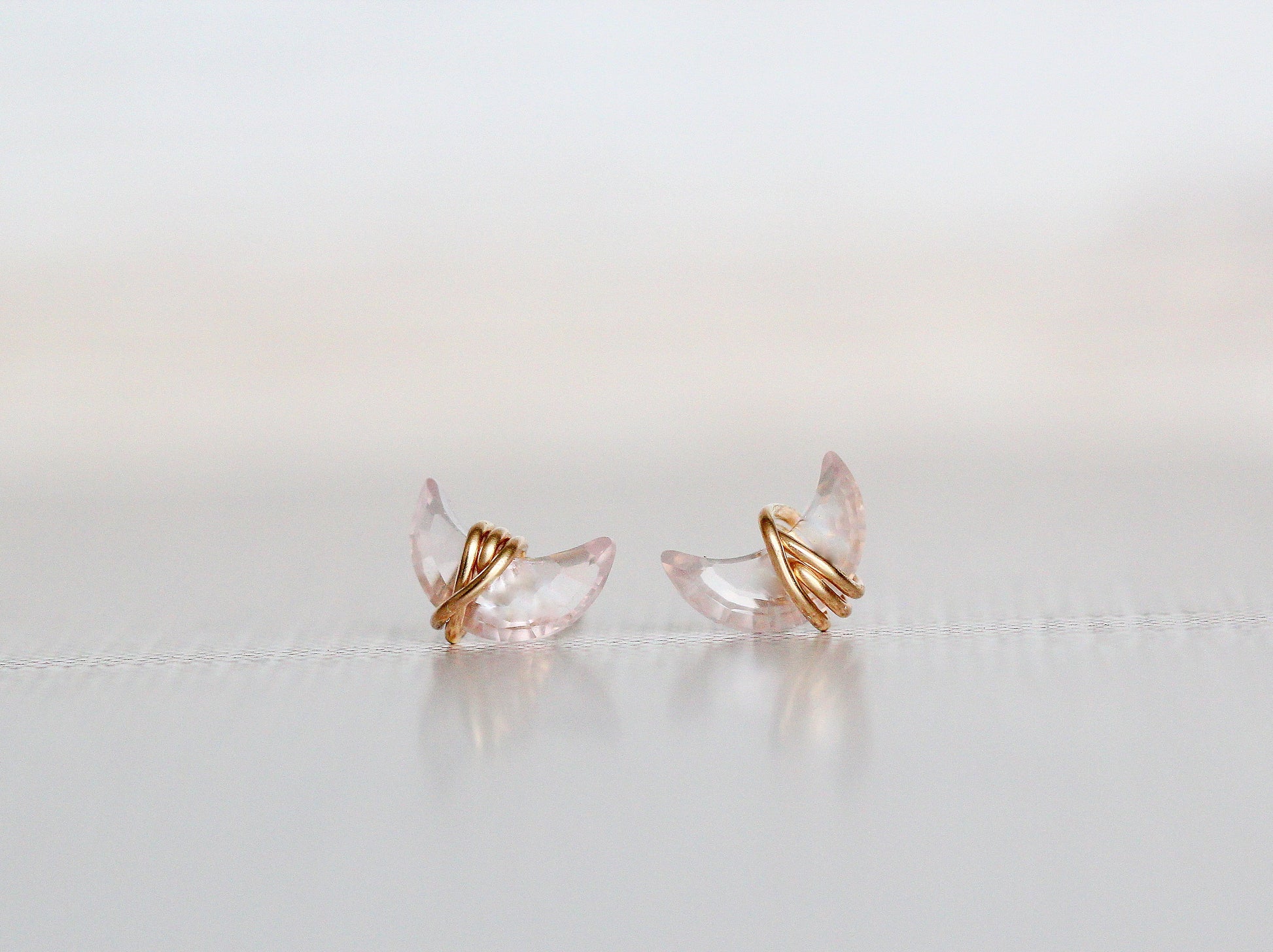 Pair of gold and clear crystal earrings on a light gray background