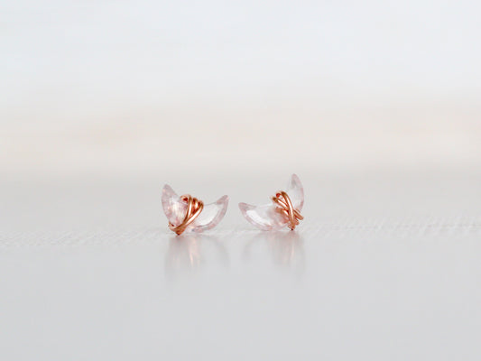 Pair of rose gold and clear crystal earrings on a light gray background