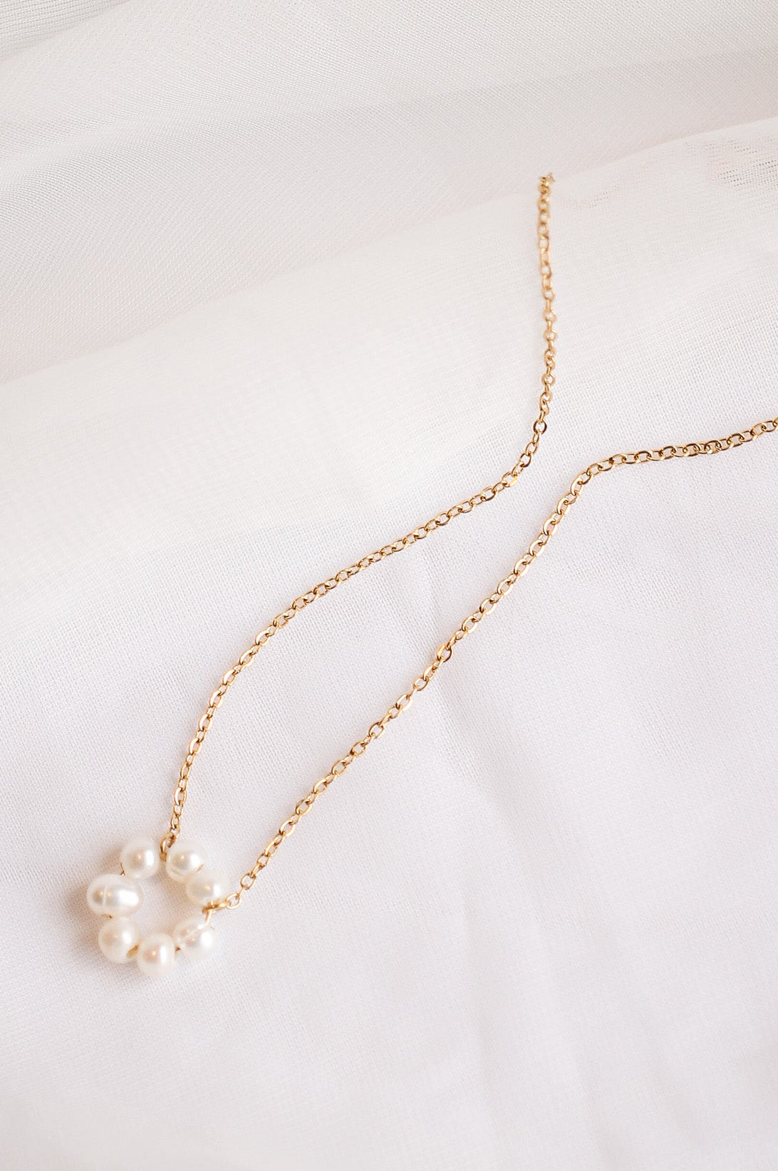Gold necklace with pearls on a white background