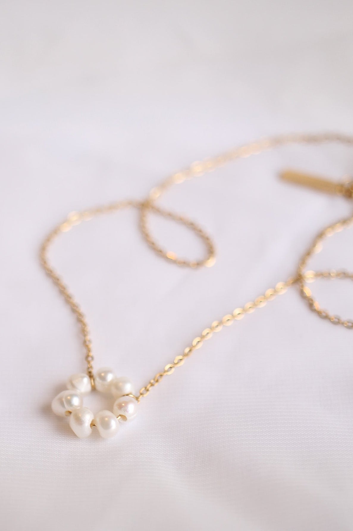 Gold necklace with a floral pendant on a light background