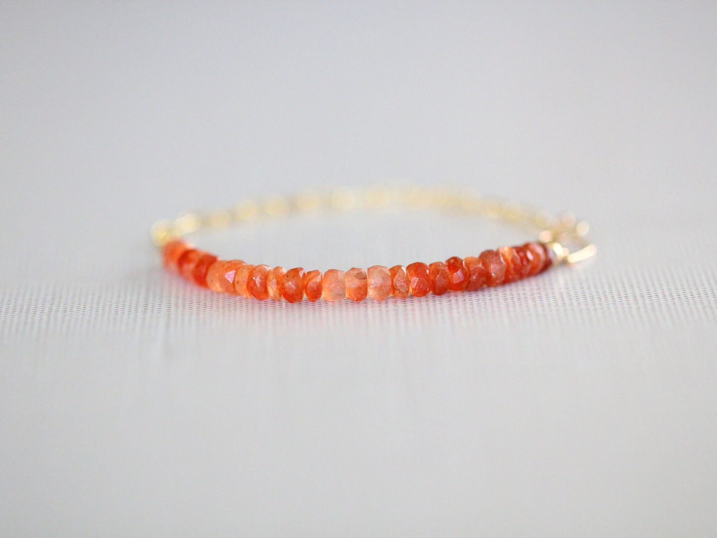 Bracelet with orange beads on a light gray background