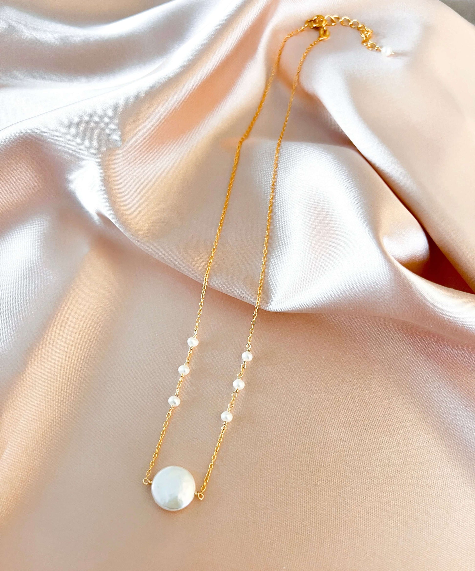 Gold necklace with pearls on a soft fabric background