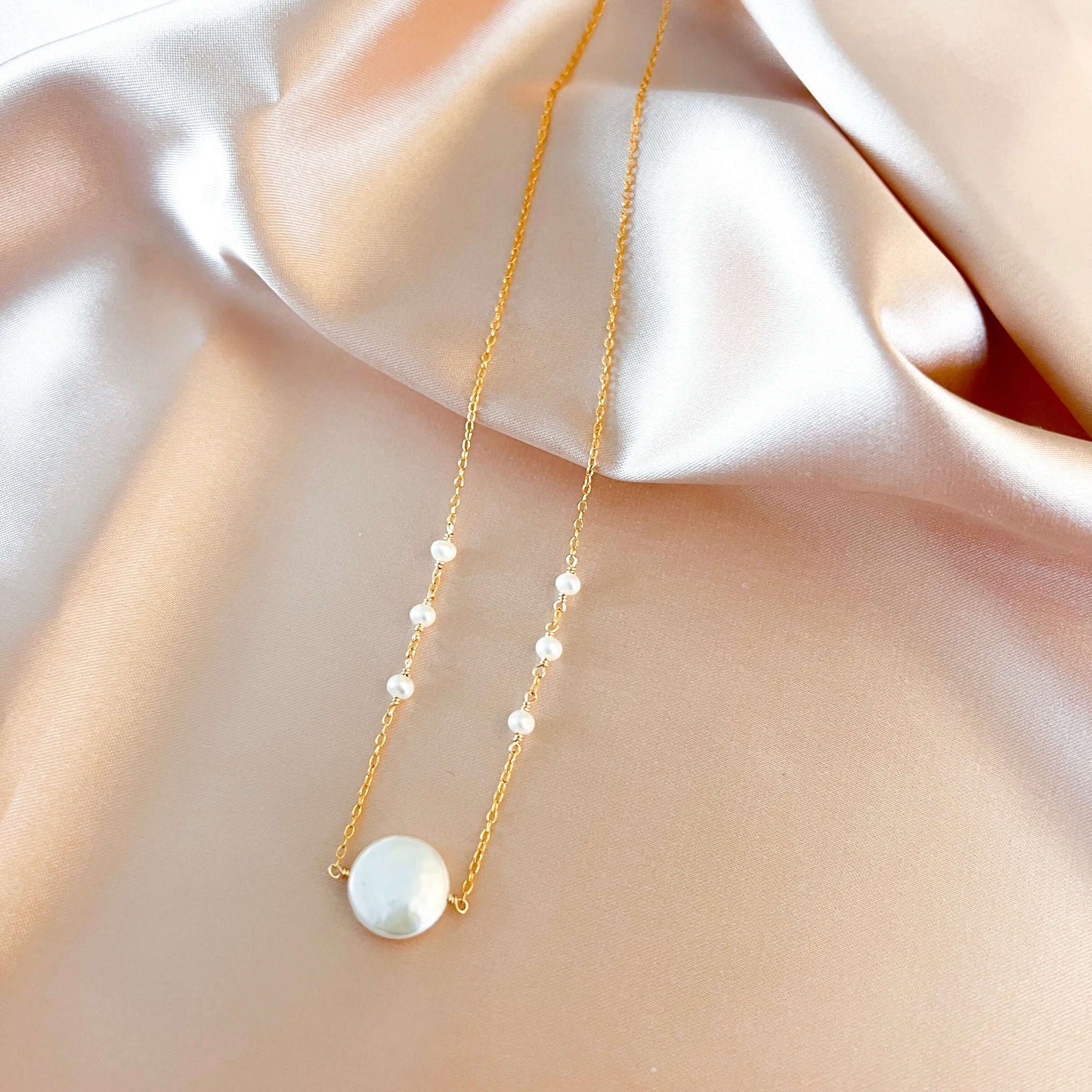 Gold necklace with pearls on a soft fabric background