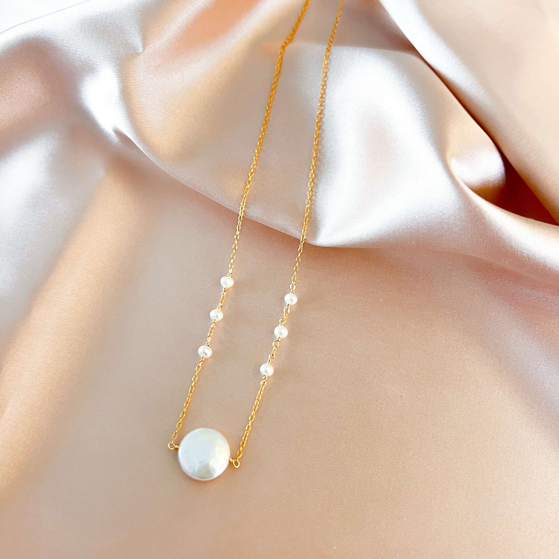 Gold necklace with pearls on a soft fabric background