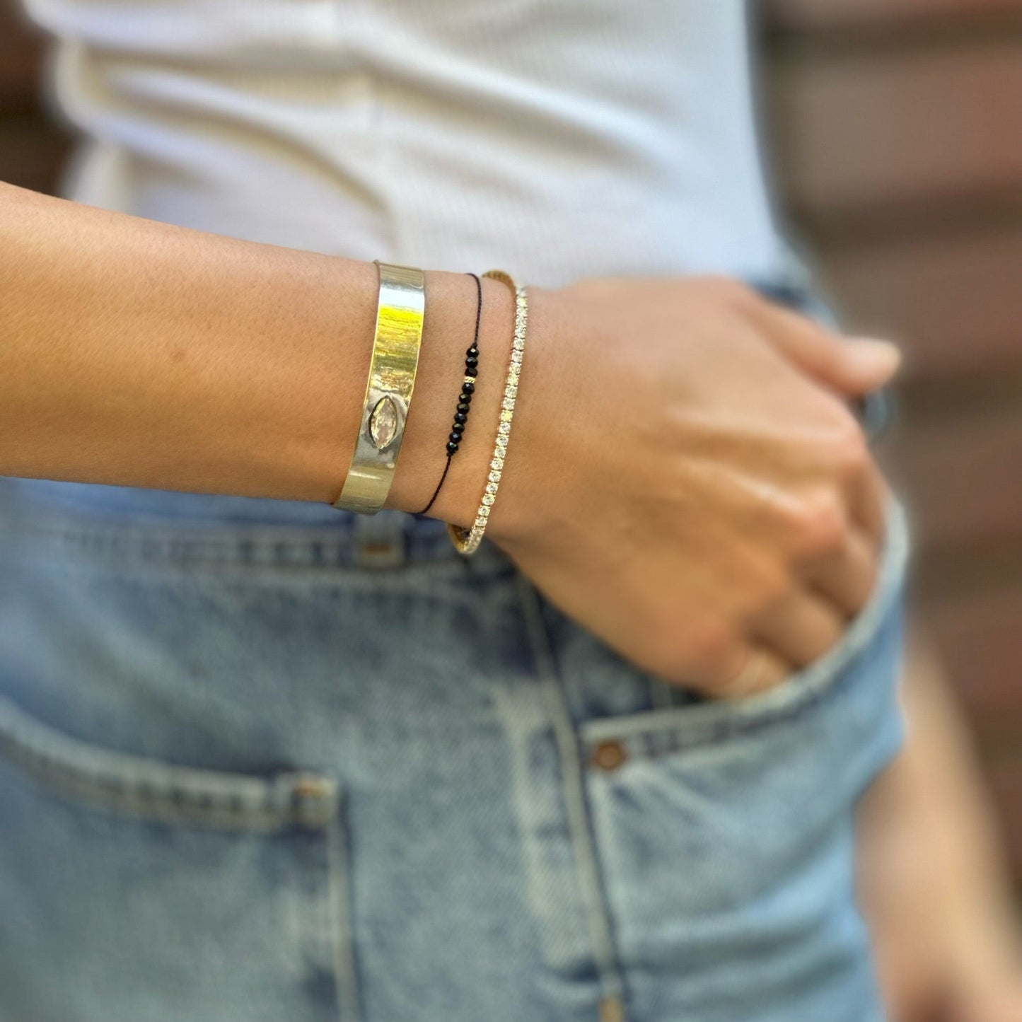 Close-up of a person's wrist with multiple bracelets on a blurred background