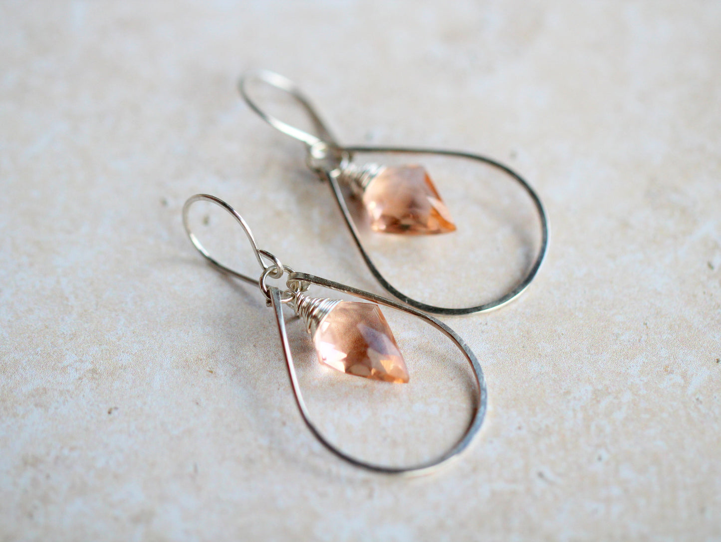 Teardrop-shaped earrings with pink gemstones on a light background