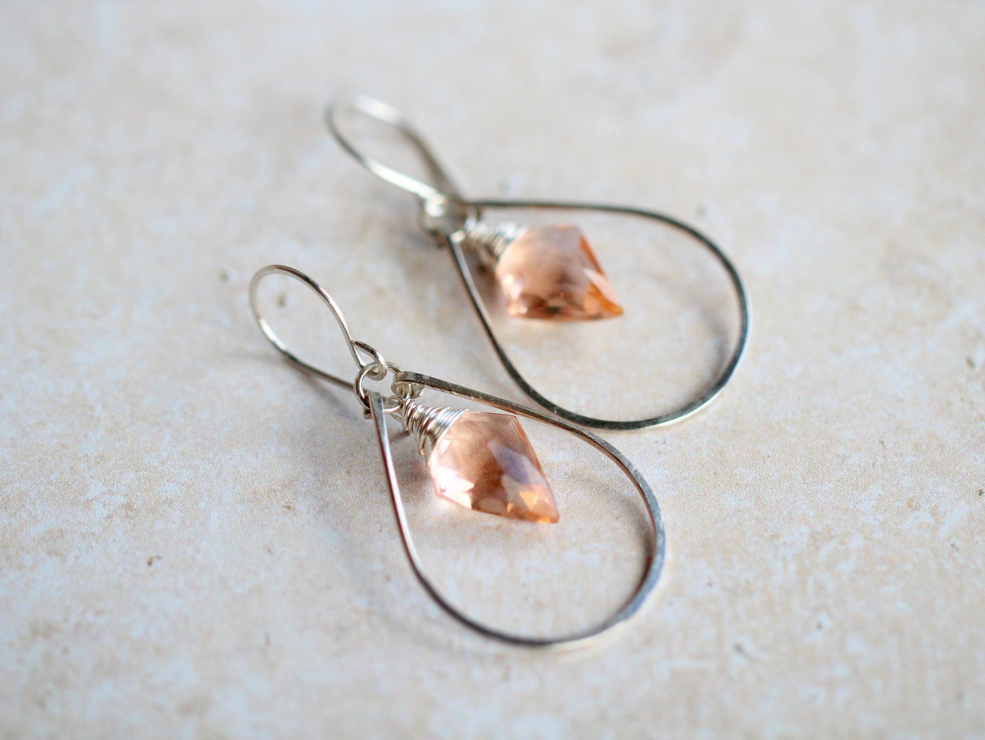 Teardrop-shaped earrings with pink gemstones on a light background