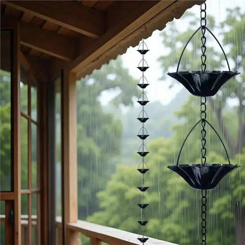 Black rain chain hanging from a wooden roof with a blurred green forest background