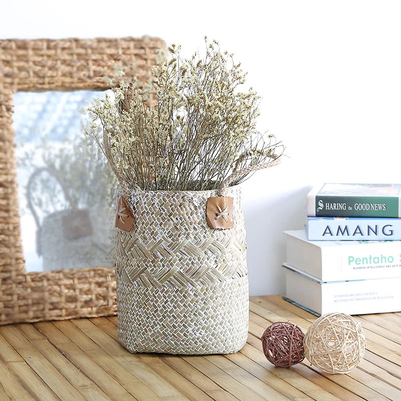 Woven basket with dried plants on a wooden surface, books in the background