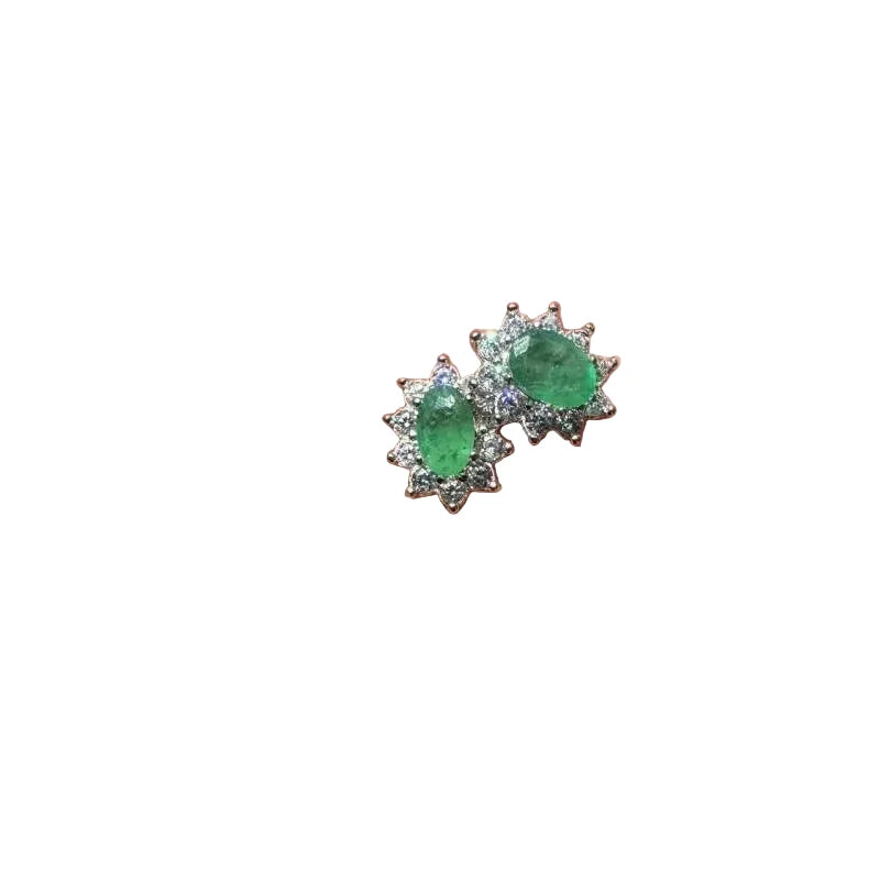 Green gemstone earrings held on a hand with a green outdoor background