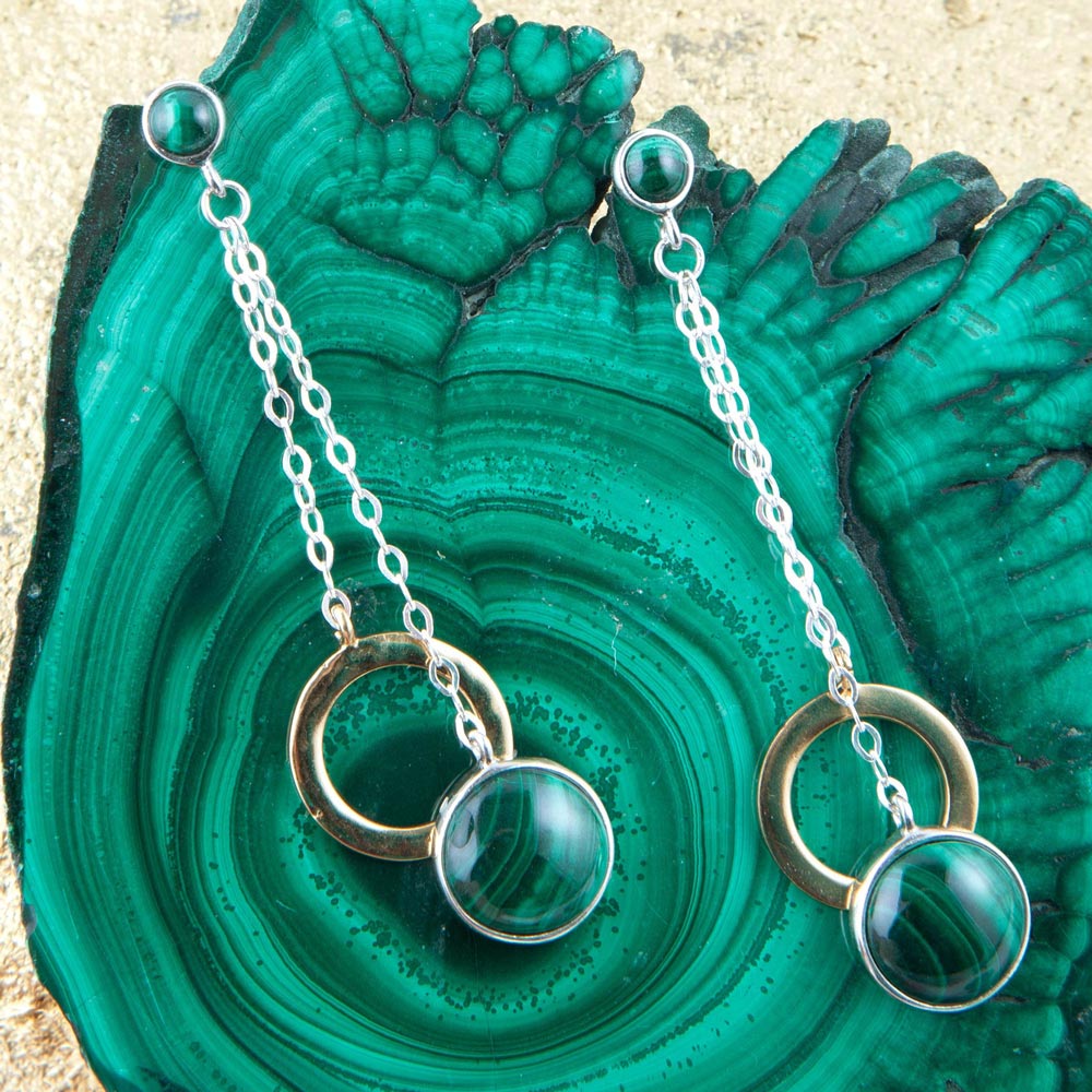 Necklace with green gemstones and gold rings on a green stone background