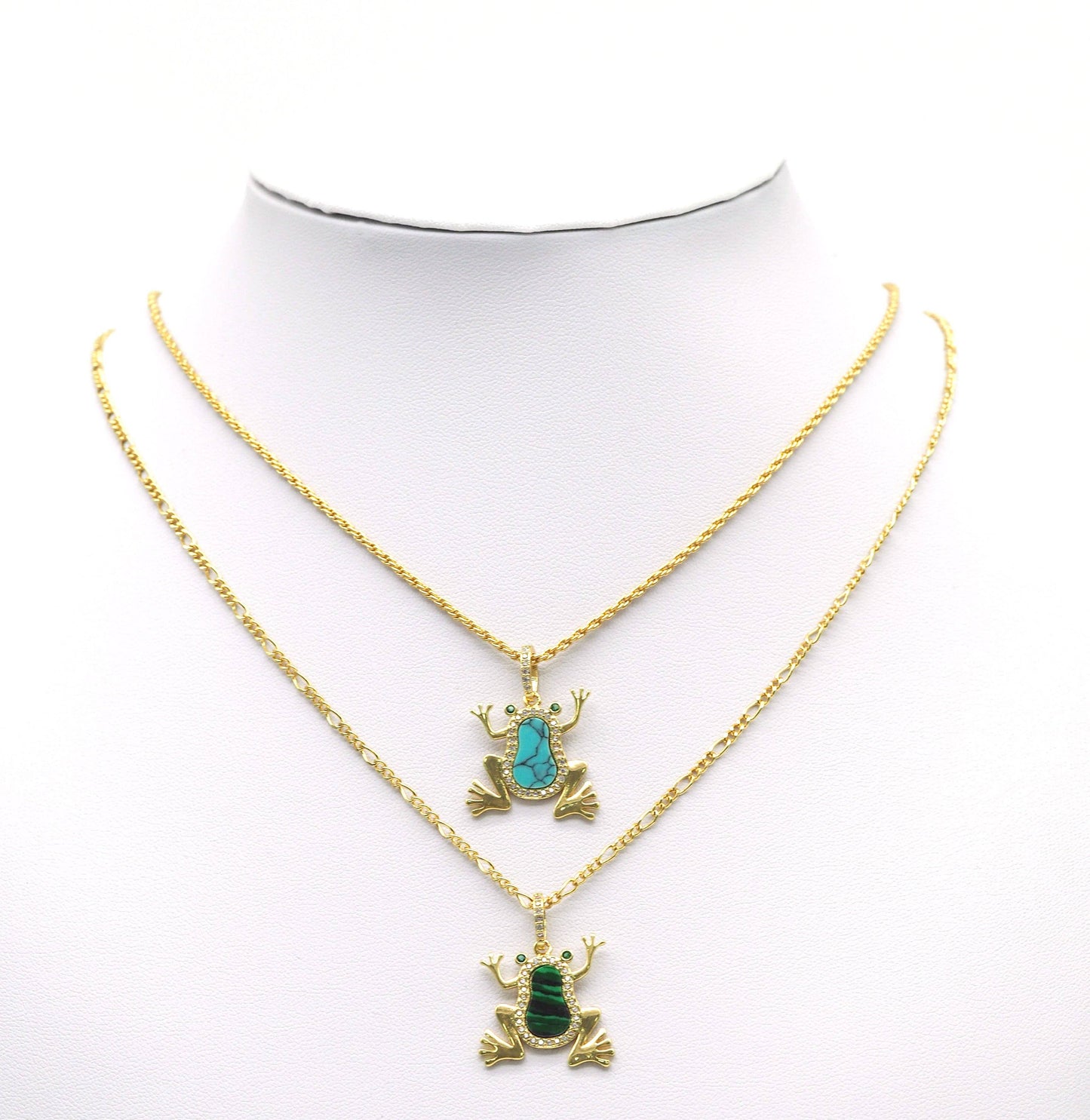 Gold necklaces with frog pendants on a mannequin bust against a white background
