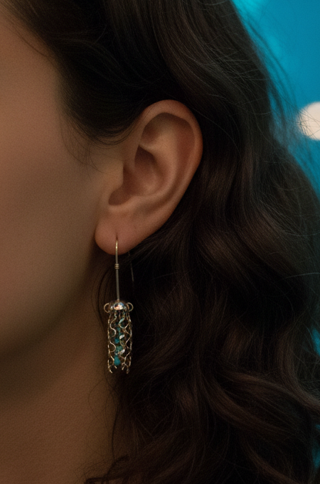 Model wearing sterling silver jellyfish earrings with turquoise beads in front of a jellyfish aquarium