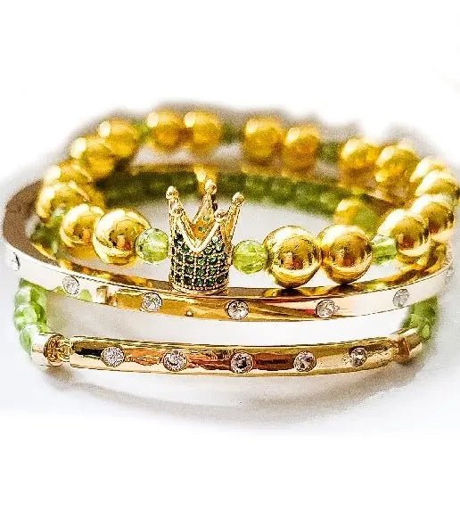 Gold and green beaded bracelet with a crown charm on a white background