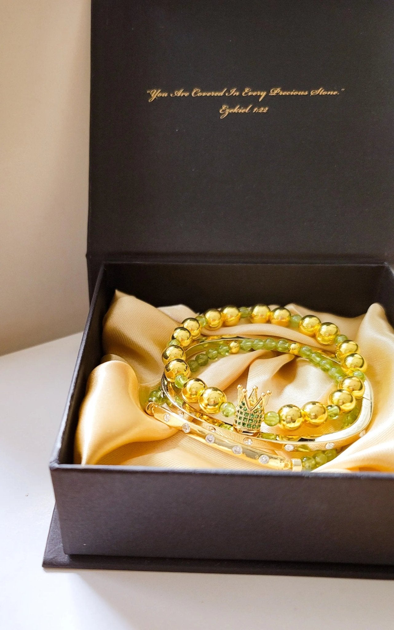 Three yellow beaded bracelets in a black box with gold interior