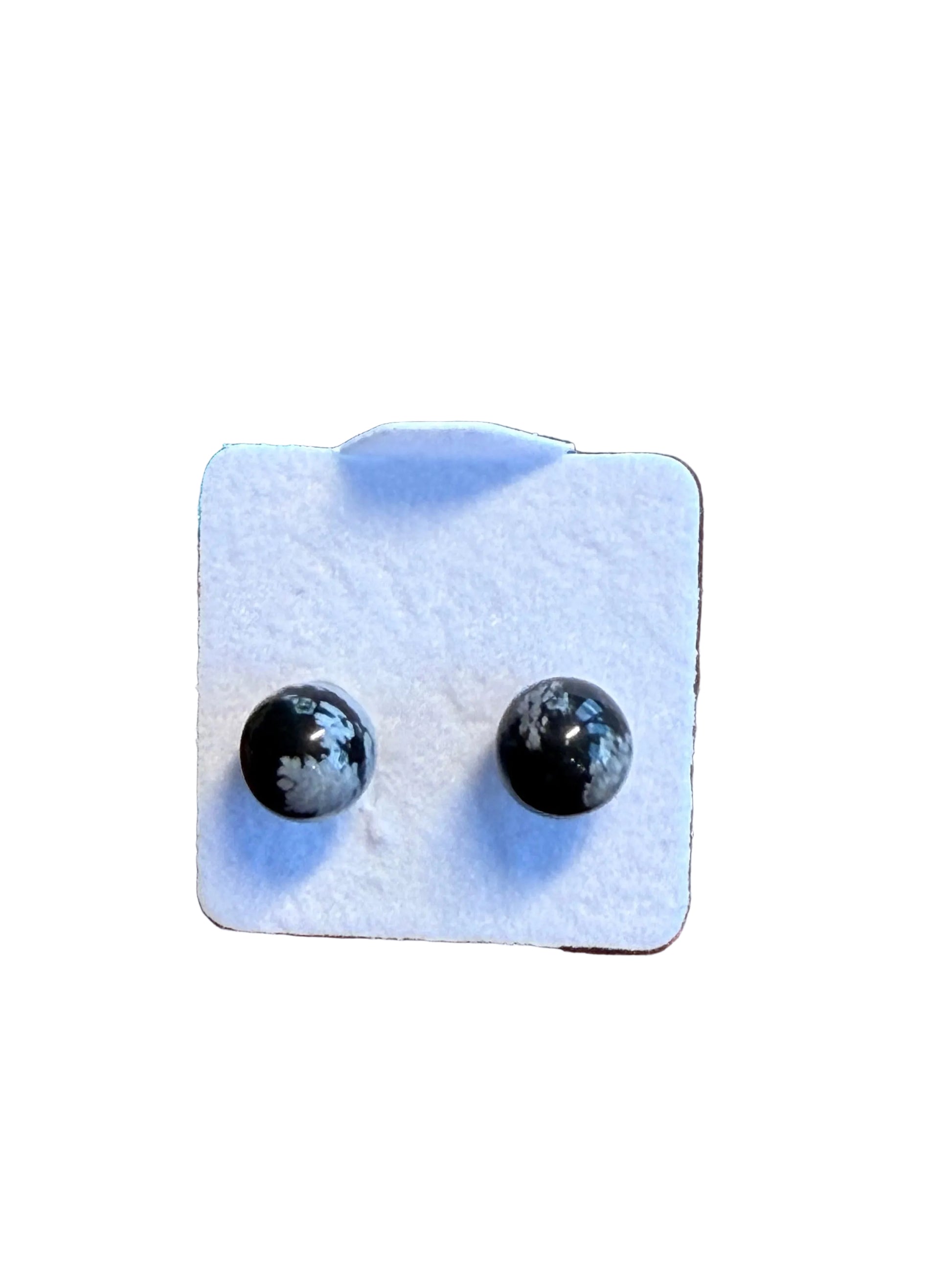 Pair of snowflake obsidian earrings on a white card against a wooden background