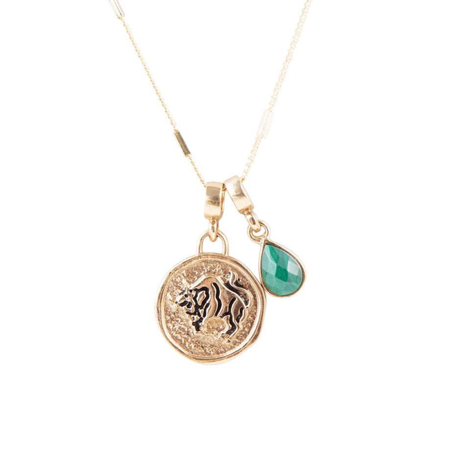 Gold necklace with lion emblem and green teardrop pendant on a white background